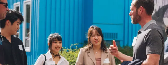 Group of people talking outdoors in front of a blue building